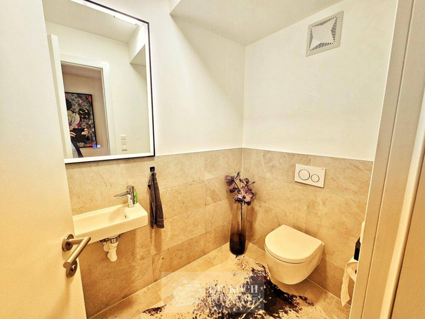 Modernes Gäste-WC mit Wand-WC, kleinem Waschbecken und beigefarbenen Fliesen.