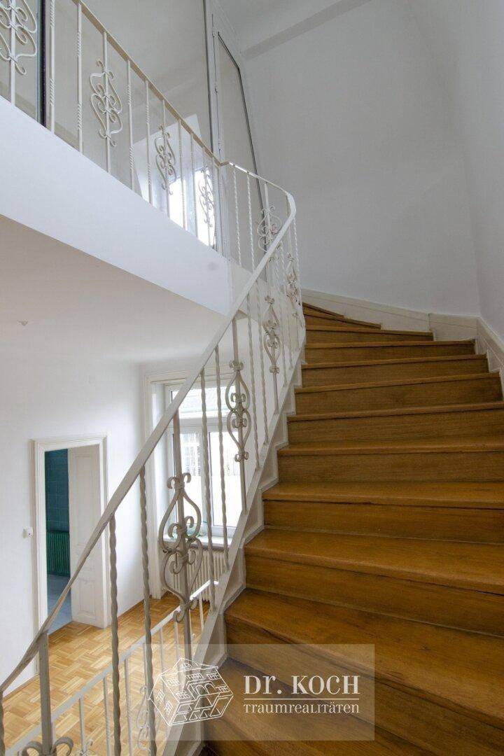 Elegante Holztreppe mit schmiedeeisernem Geländer, verbindet die Etagen.