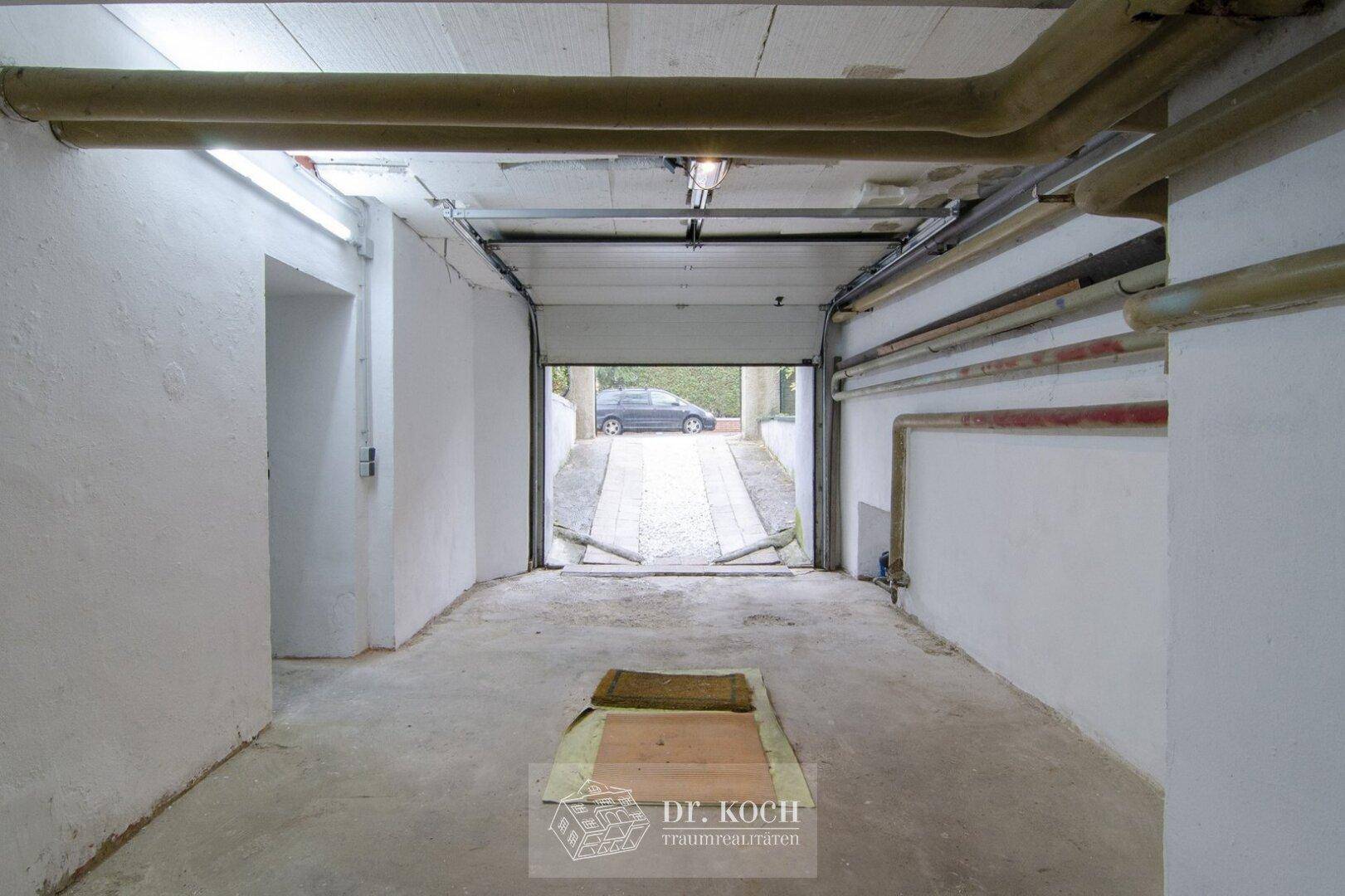 Tiefgaragenzufahrt mit Betonboden und sichtbaren Versorgungsleitungen.