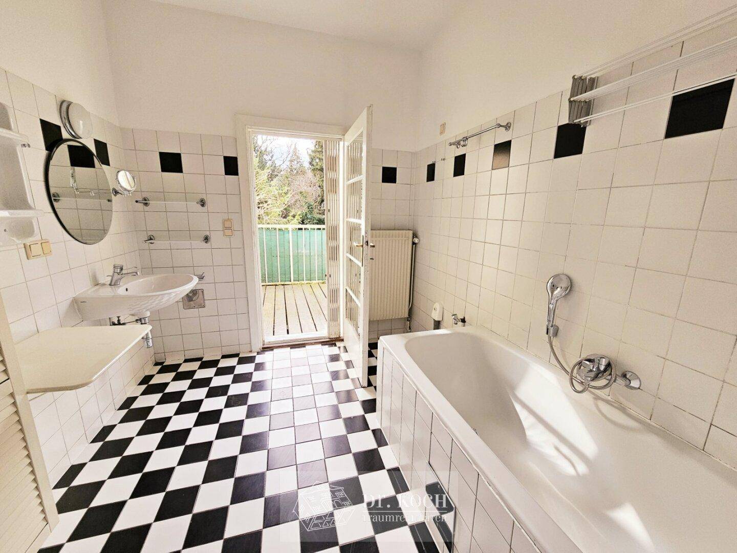 Badezimmer mit schwarz-weiß karierten Fliesen, Badewanne und Zugang zu einem kleinen Balkon.
