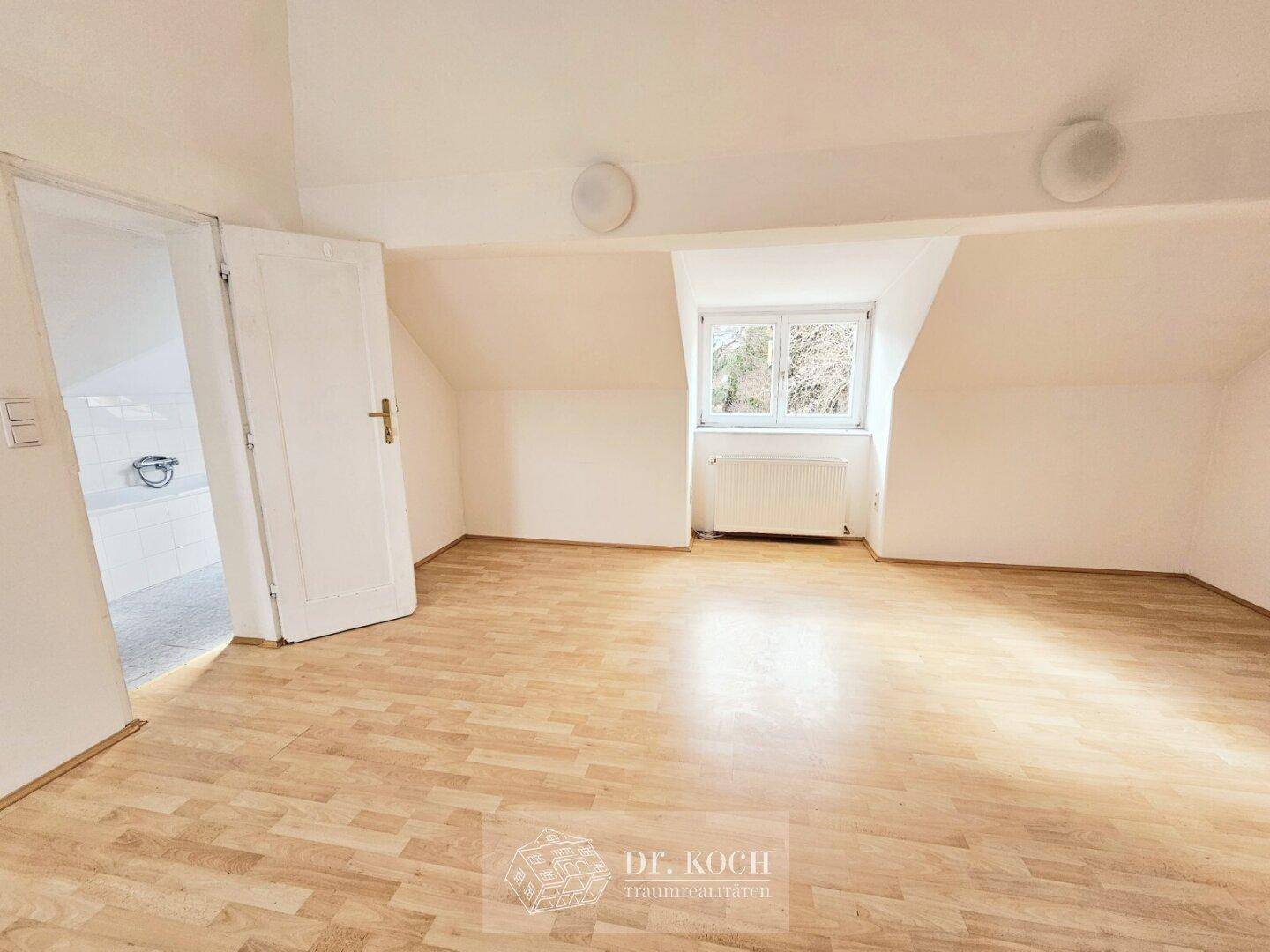 Helles Schlafzimmer im Dachgeschoss mit Laminatboden und schrägen Wänden.
