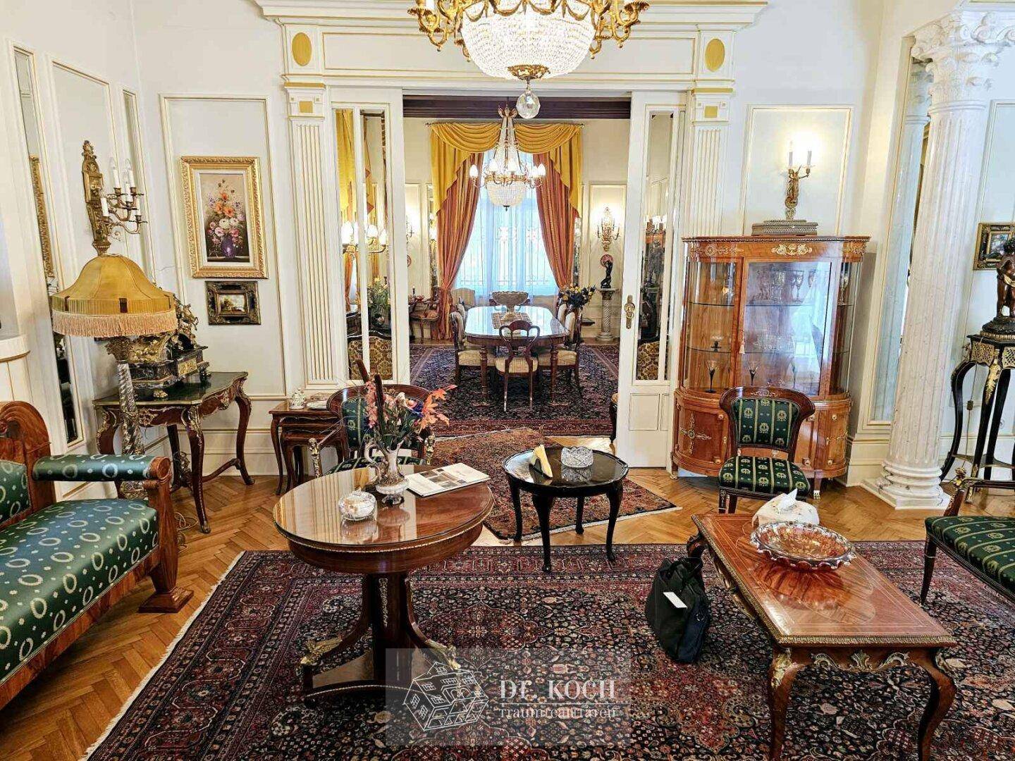 Elegantes Wohnzimmer mit klassischem Mobiliar, Parkettboden und Blick in den angrenzenden Essbereich.