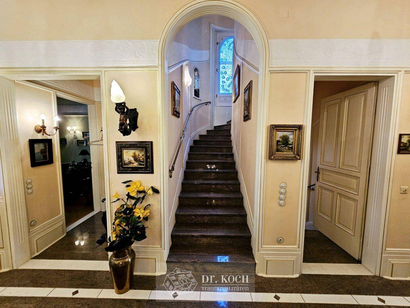 Geräumiger Flur mit eleganter Treppe, die in die oberen Etagen führt, und Marmorboden.