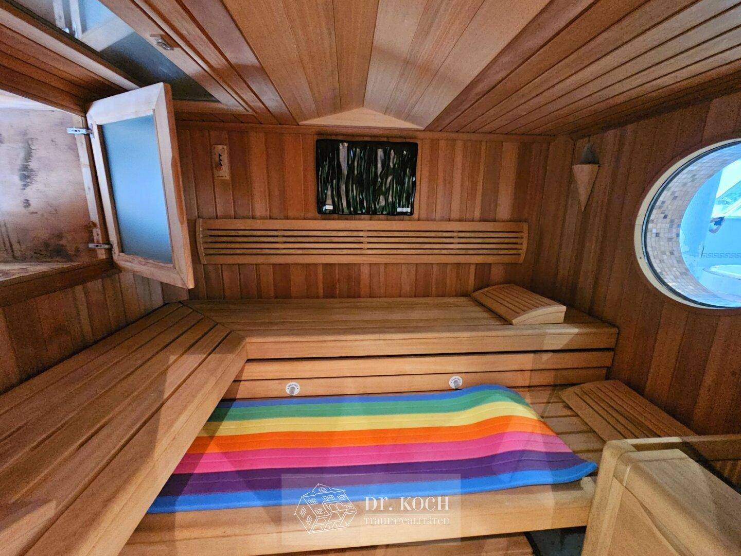 Moderne Holzsauna mit bequemen Bänken und einem runden Fenster für Entspannung.