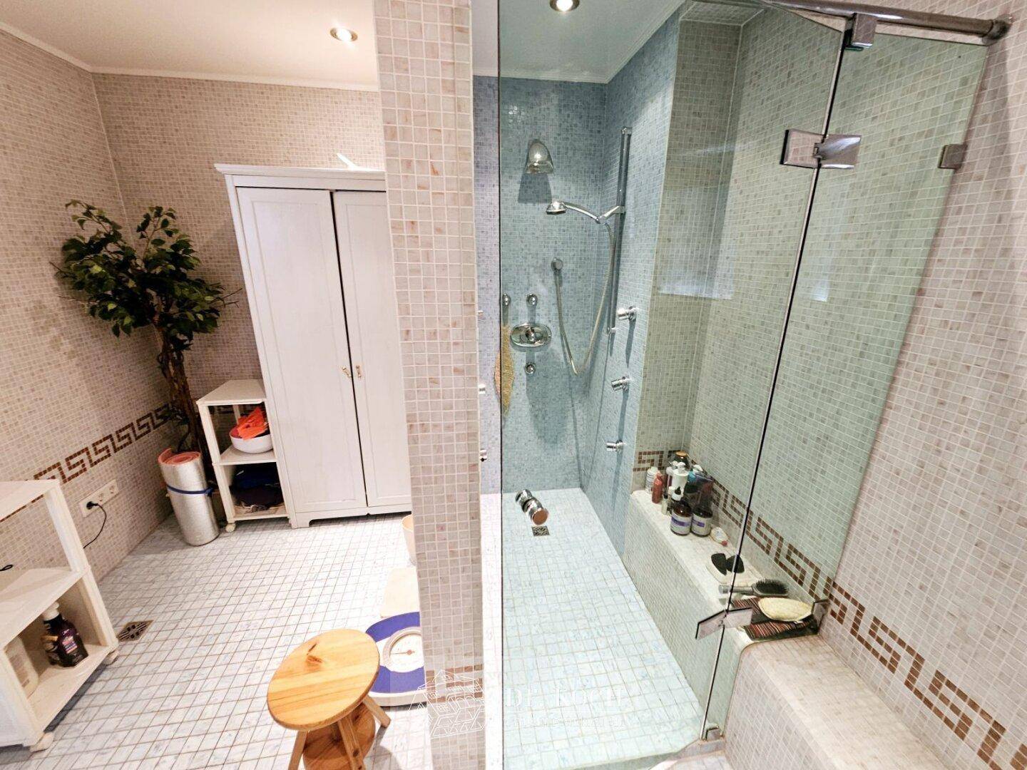 Modernes Badezimmer mit Mosaikfliesen, begehbarer Dusche und minimalistischer Einrichtung.