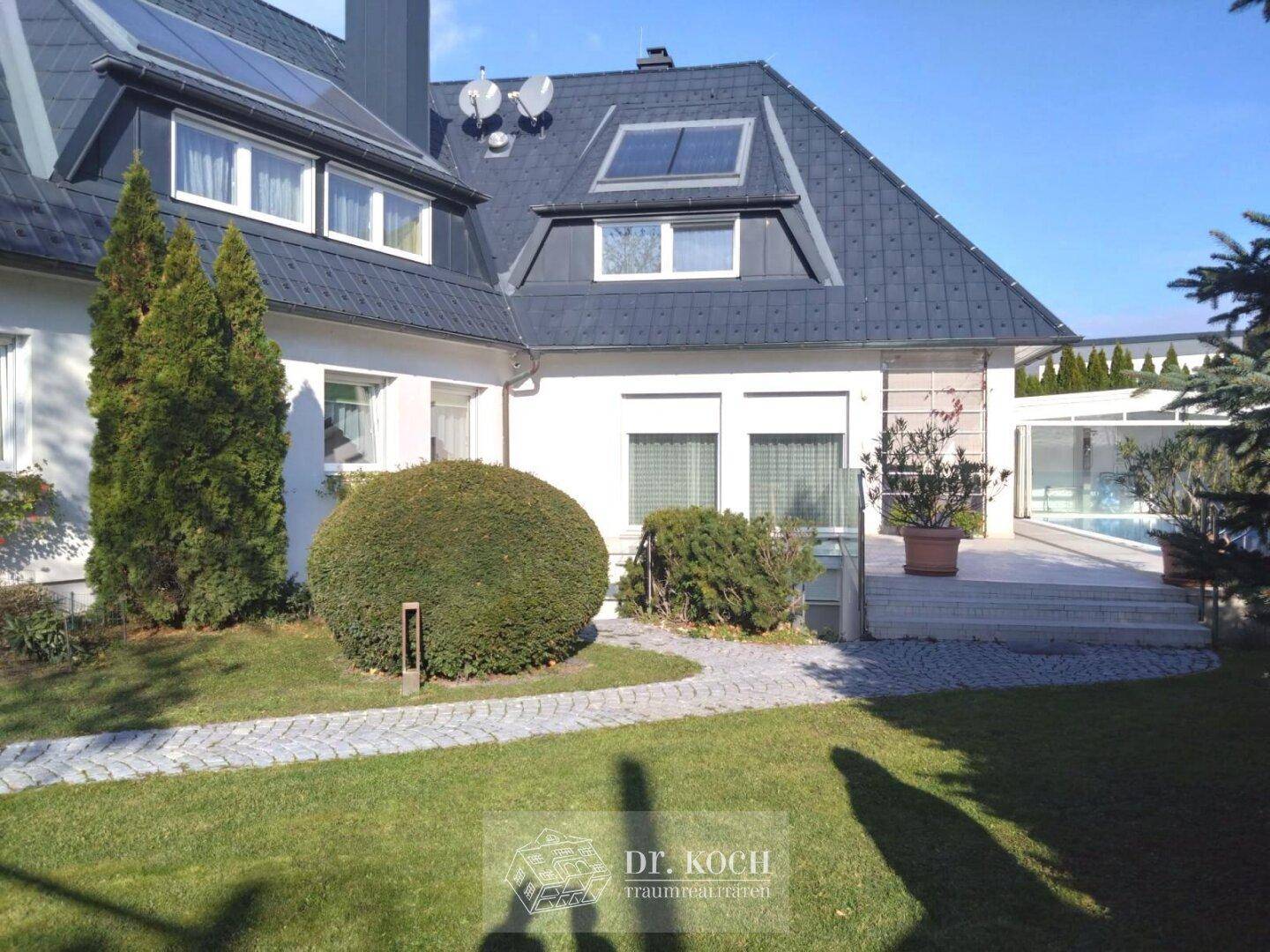 Ansicht des Hauses mit gepflegtem Vorgarten, Steinweg und Solaranlagen auf dem Dach.