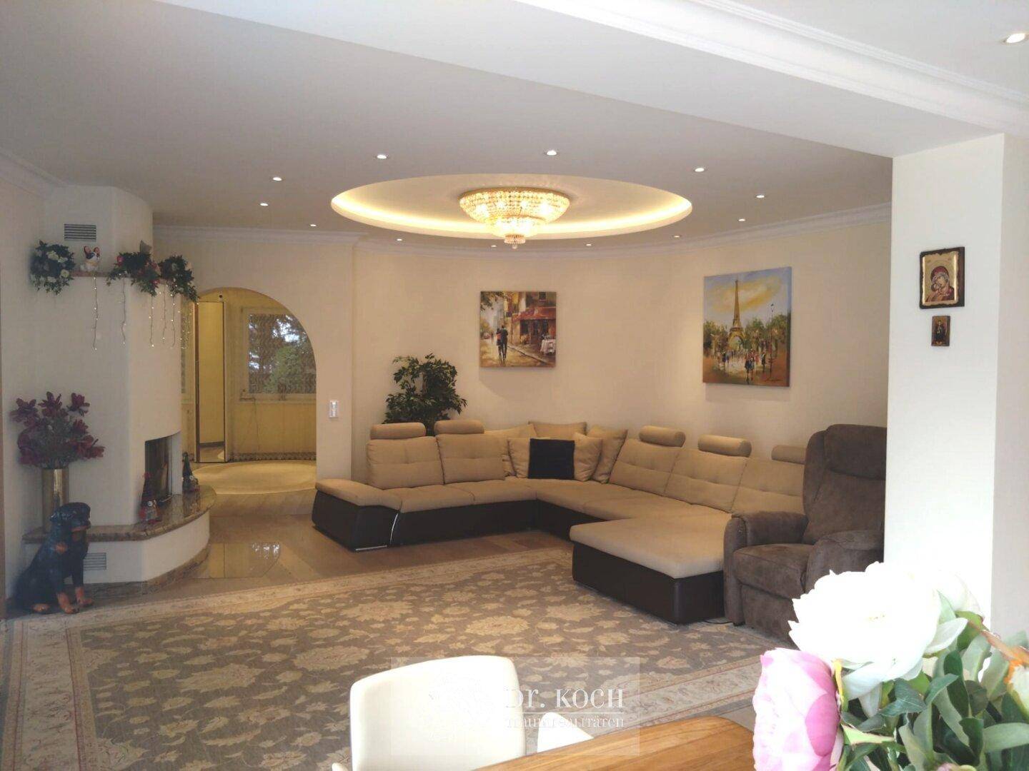 Geräumiges Wohnzimmer mit großem Ecksofa, Kamin und indirekter Deckenbeleuchtung.