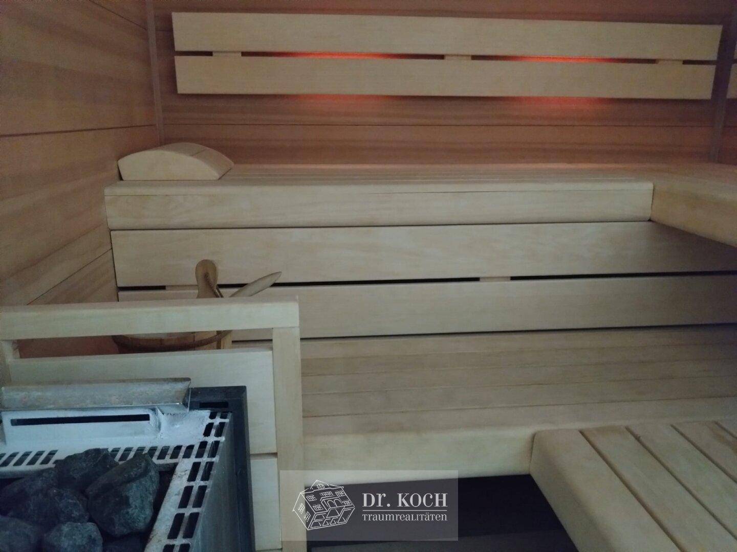 Holzvertäfelte Sauna mit Bänken und Heizofen für entspannende Momente.