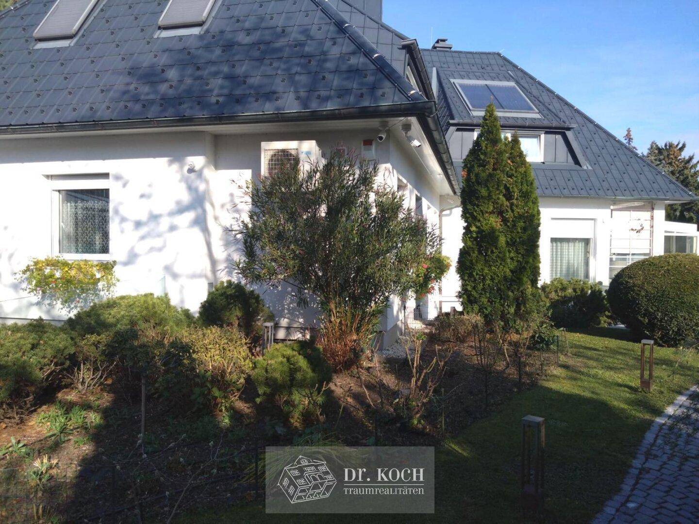 Seitenansicht des Hauses mit gepflegtem Gartenbereich und Zugangsweg.