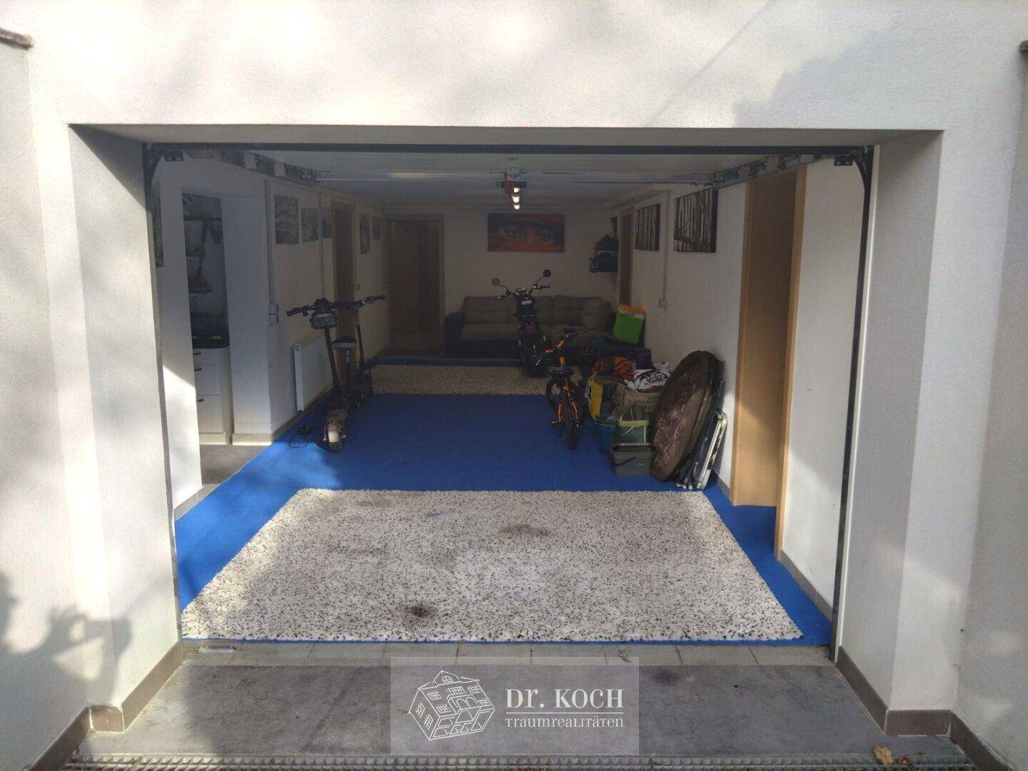Geräumige Garage mit blauem Boden, genutzt als Abstell- und Freizeitbereich.