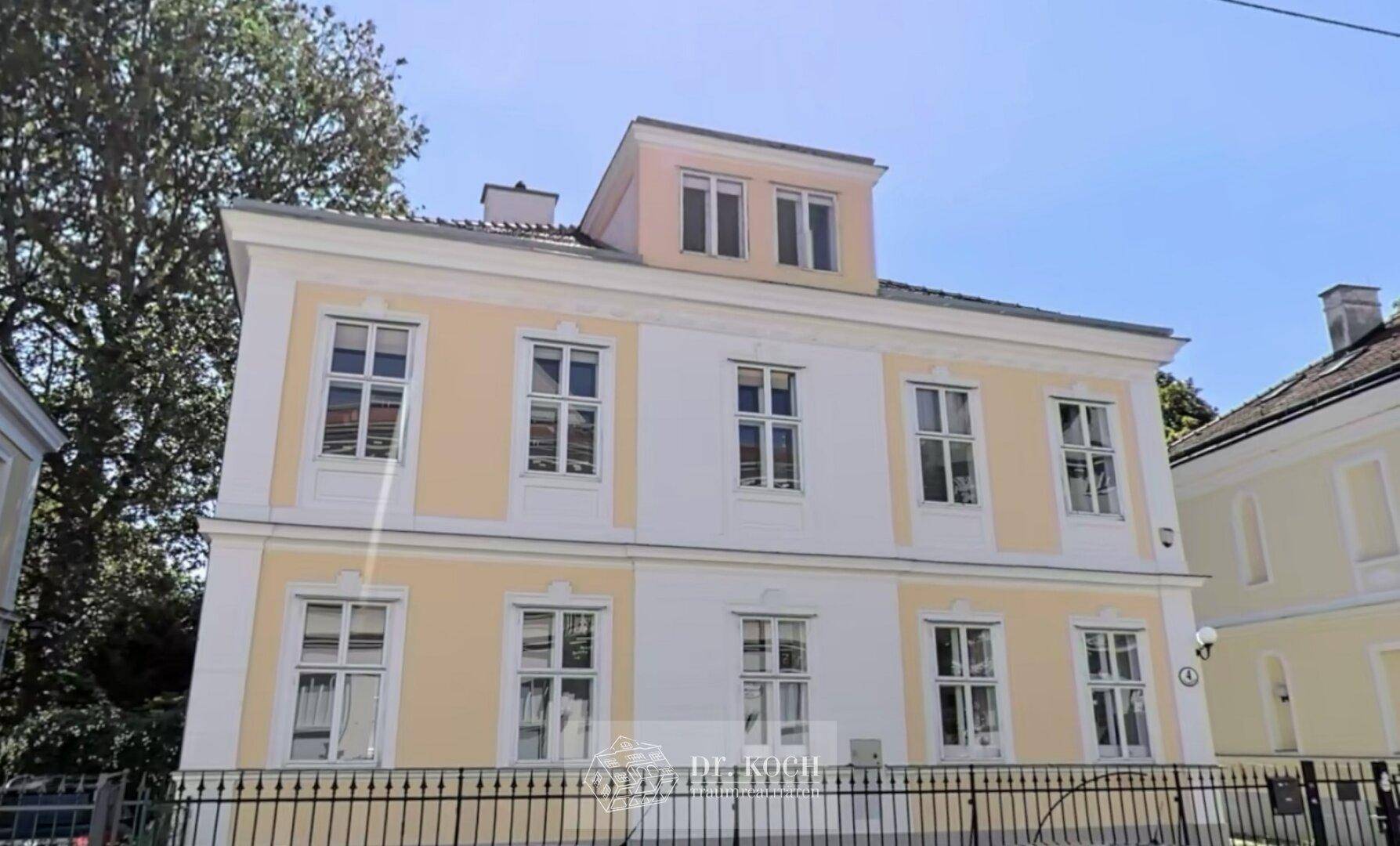 Klassische Fassade eines Altbaus mit hellgelben Akzenten und weißen Fensterrahmen.