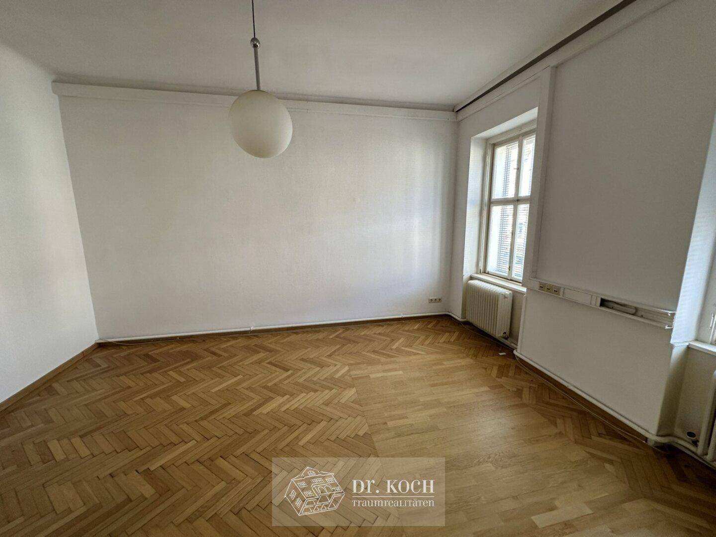 Geräumiges Schlafzimmer mit Fischgrätparkett und einem großen Fenster für viel Tageslicht.
