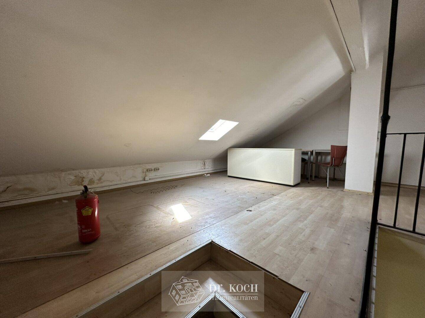 Ausgebauter Dachboden mit schrägen Wänden, Holzboden und einem Dachfenster.
