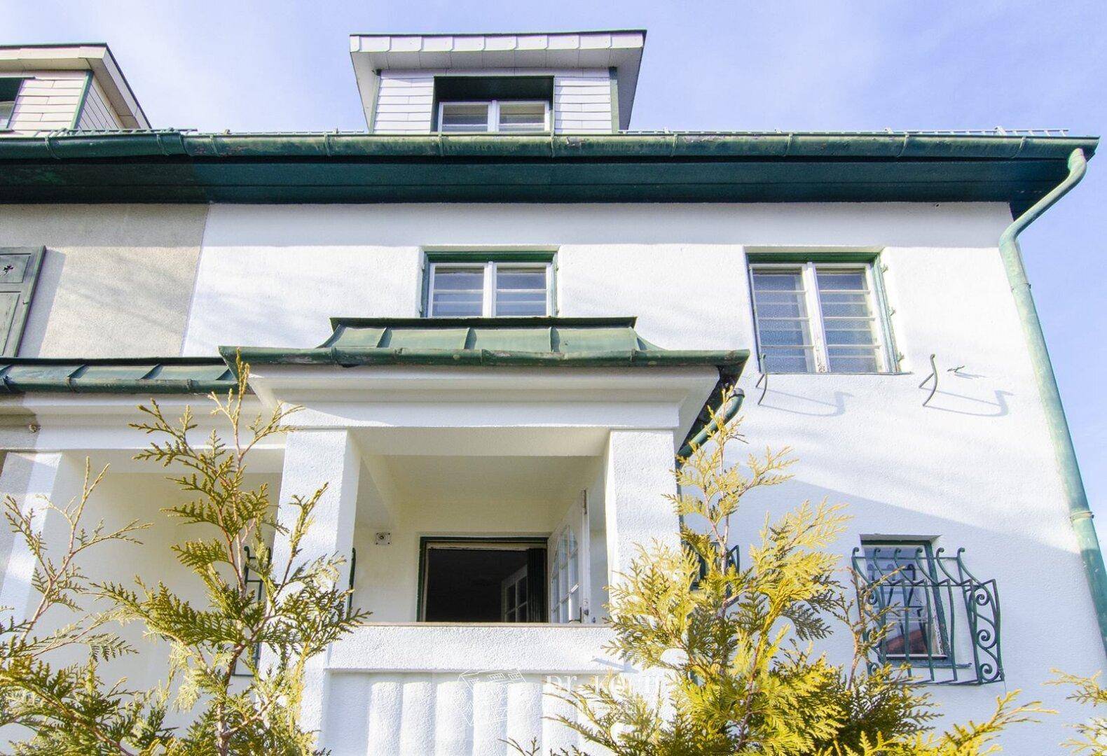 Detailansicht der Fassade mit überdachtem Eingangsbereich und Fenstern.