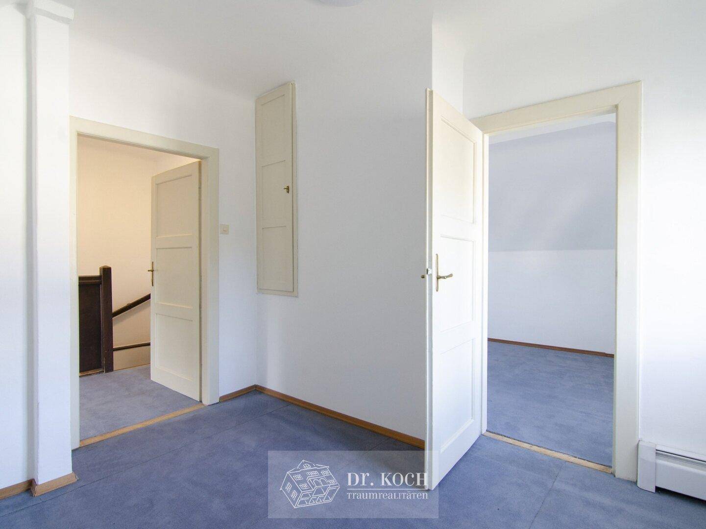 Heller Flur im Dachgeschoss mit Teppichboden und Zugang zu weiteren Räumen.