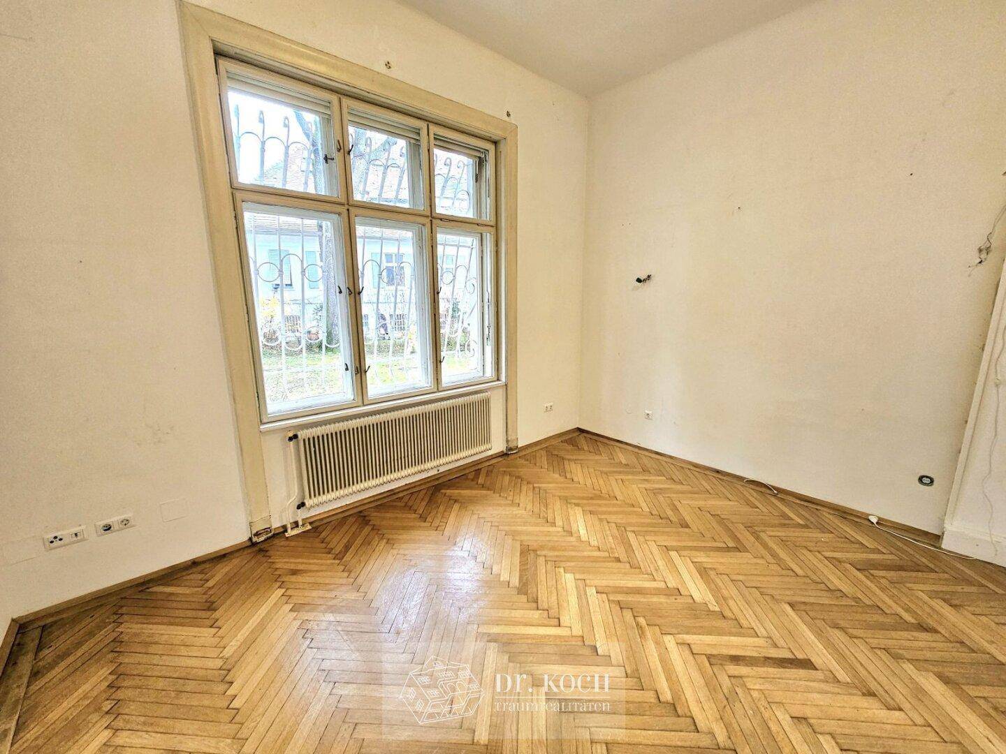 Geräumiges Zimmer mit Fischgrätparkett und großen Fenstern, vielseitig nutzbar als Schlaf- oder Arbeitszimmer.