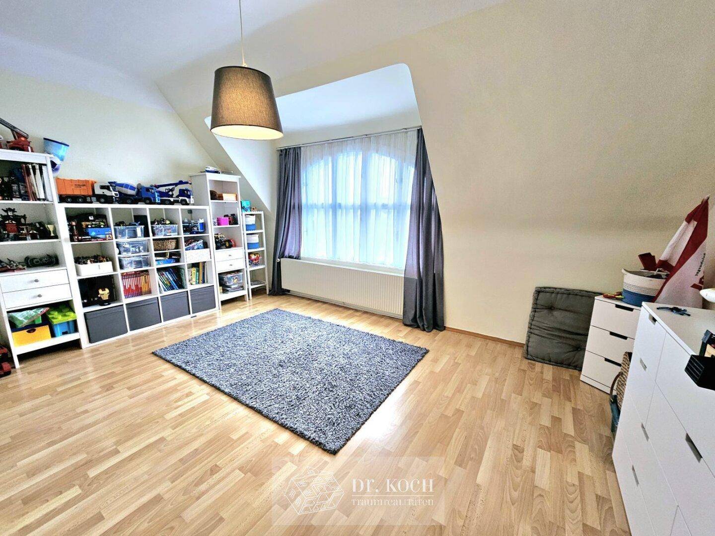 Helles Schlafzimmer im Dachgeschoss mit schräger Decke, großem Fenster und Stauraum.