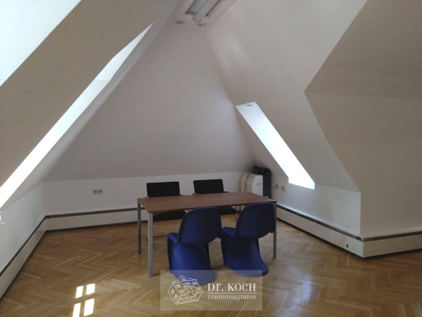 Dachgeschossraum mit schrägen Wänden, Holzboden und einem einfachen Tisch mit Stühlen, bietet flexible Nutzung.
