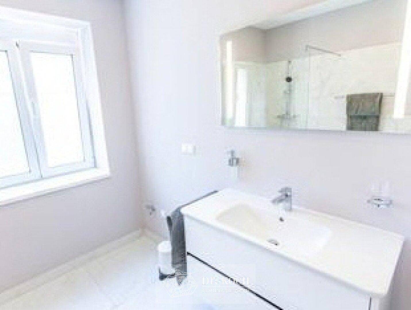 Modernes Badezimmer mit Einzelwaschbecken, großer Spiegelfläche und Fenster.