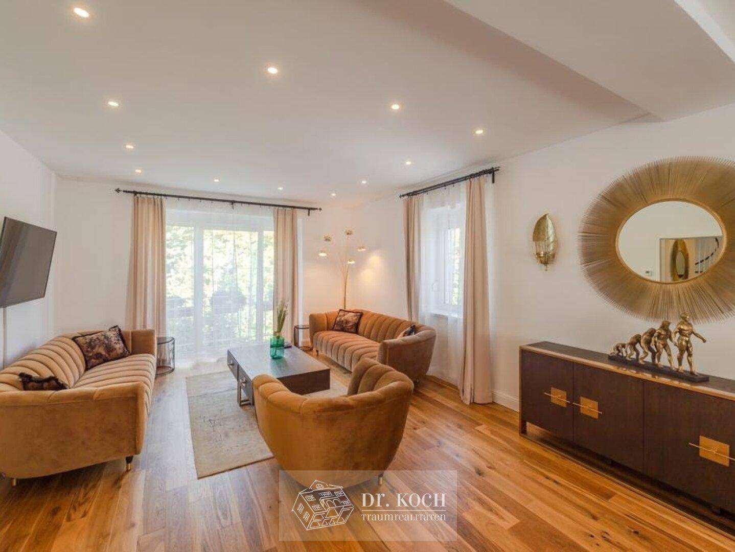 Stilvolles Wohnzimmer mit zwei Sofas, Holzboden und Zugang zu einem Balkon oder einer Terrasse.