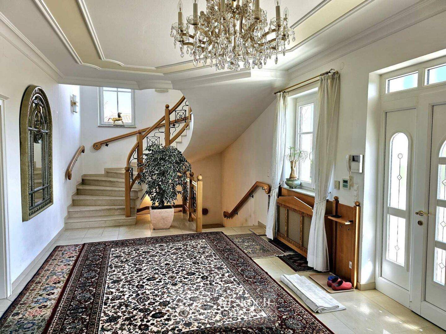 Repräsentativer Eingangsbereich mit eleganter Marmortreppe, Kronleuchter und hohen Decken.
