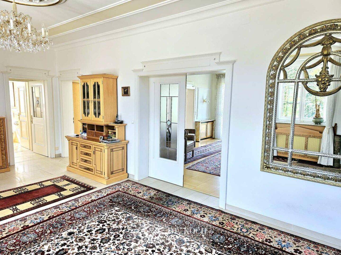Heller Flur mit elegantem Teppich, Holzmöbeln und Zugang zu weiteren Räumen im Haus.
