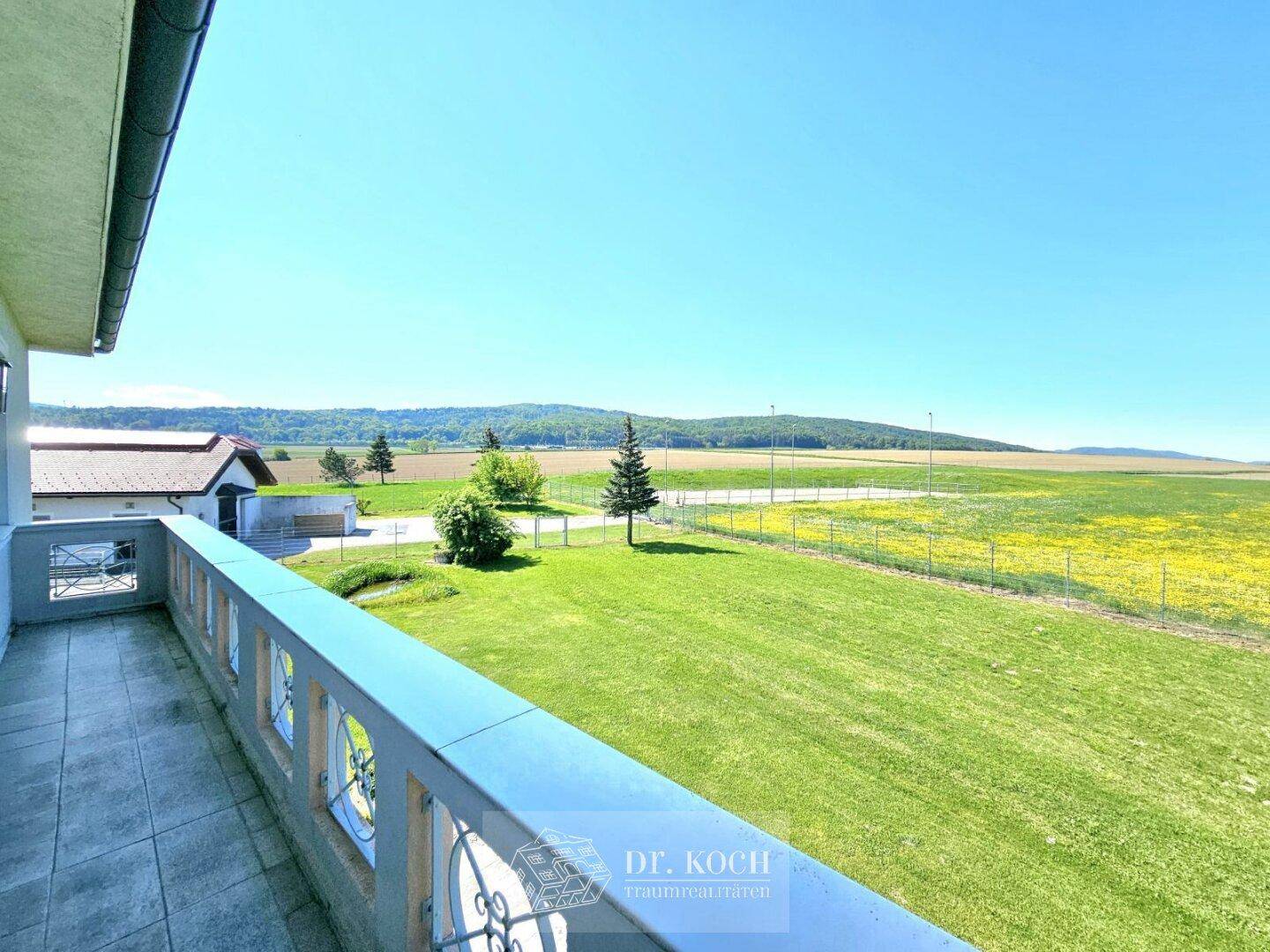 Geräumiger Balkon mit weitem Blick über die grüne Landschaft und die umliegenden Felder.