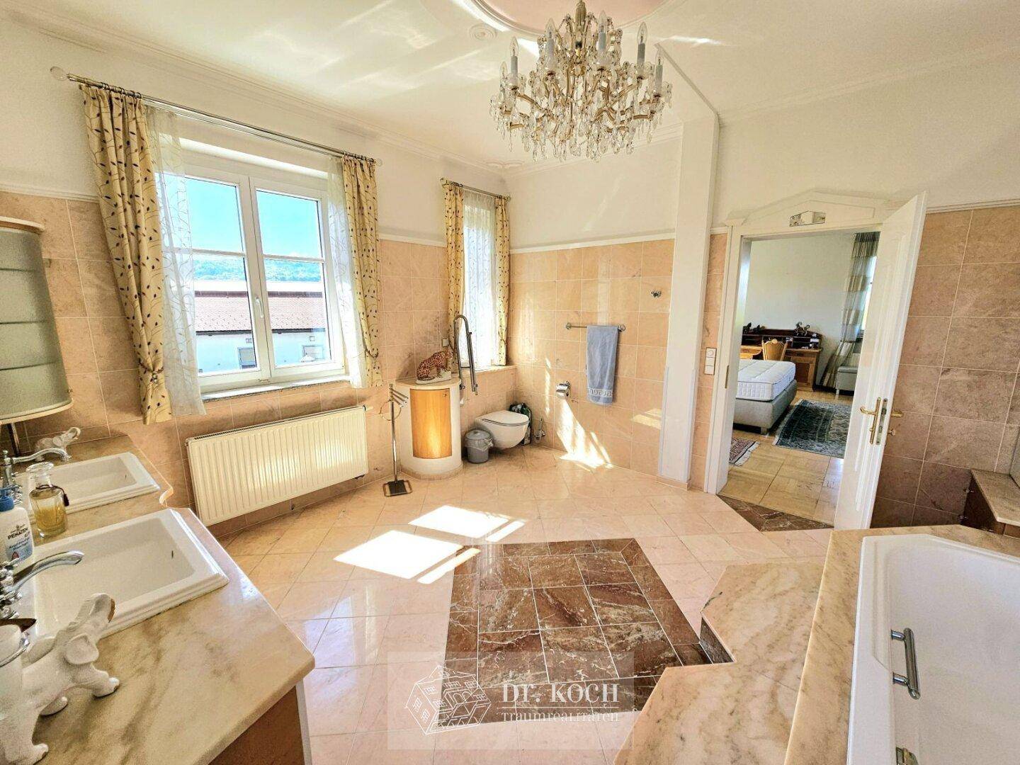 Geräumiges Badezimmer mit Badewanne, Doppelwaschbecken und Fenster, bietet helles Ambiente.