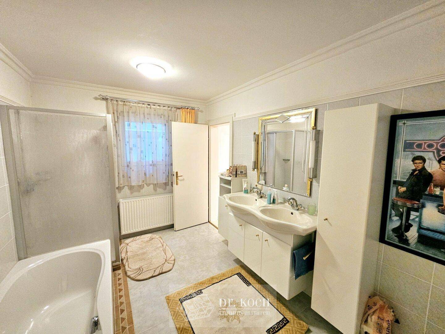 Badezimmer mit Doppelwaschbecken, Badewanne und separater Duschkabine.