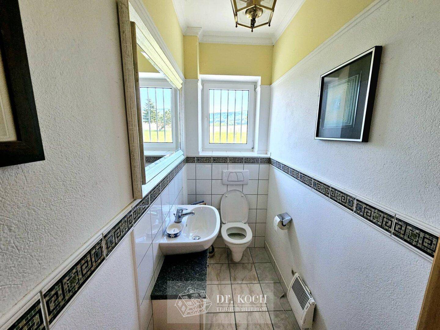 Kleines Gäste-WC mit Fenster, Waschbecken und Wandfliesen.