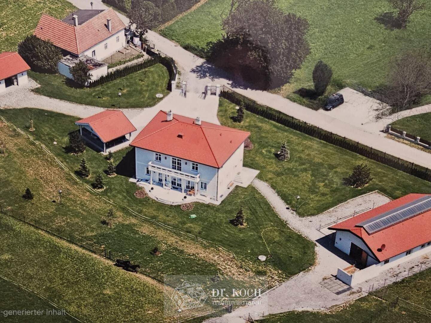 Luftaufnahme eines Anwesens mit mehreren Gebäuden, viel Grünfläche und Wegen.