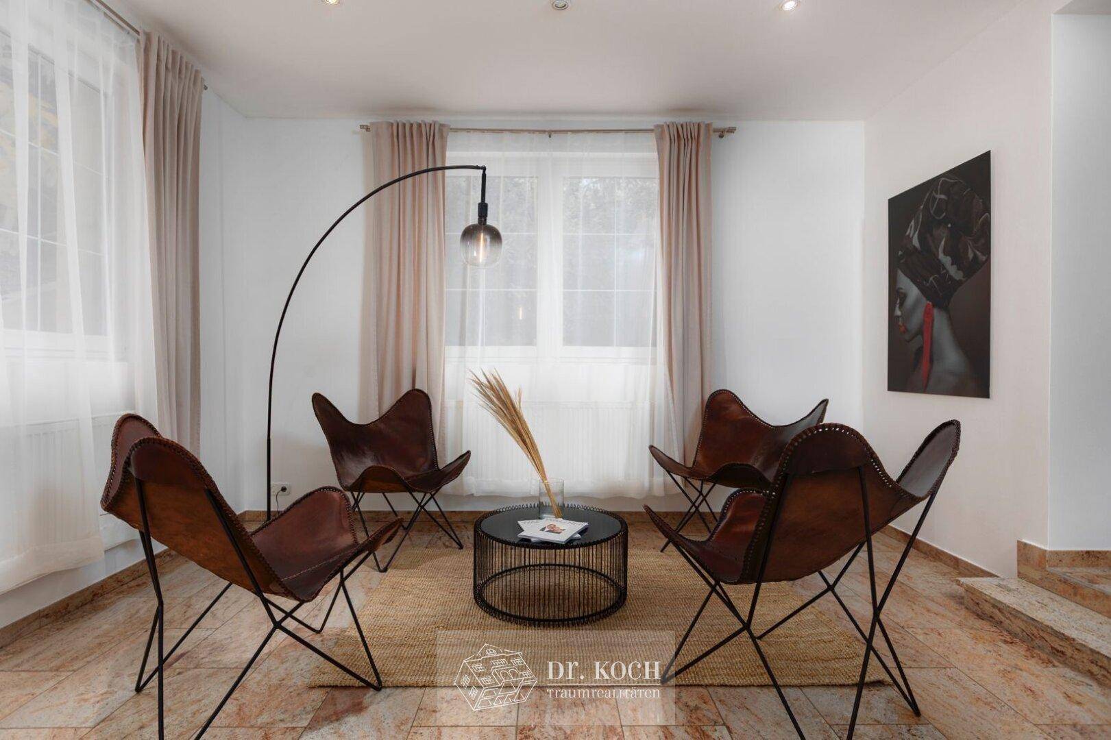 Gemütliche Sitzecke im Wohnzimmer mit Ledersesseln, Stehlampe und glänzendem Marmorboden.