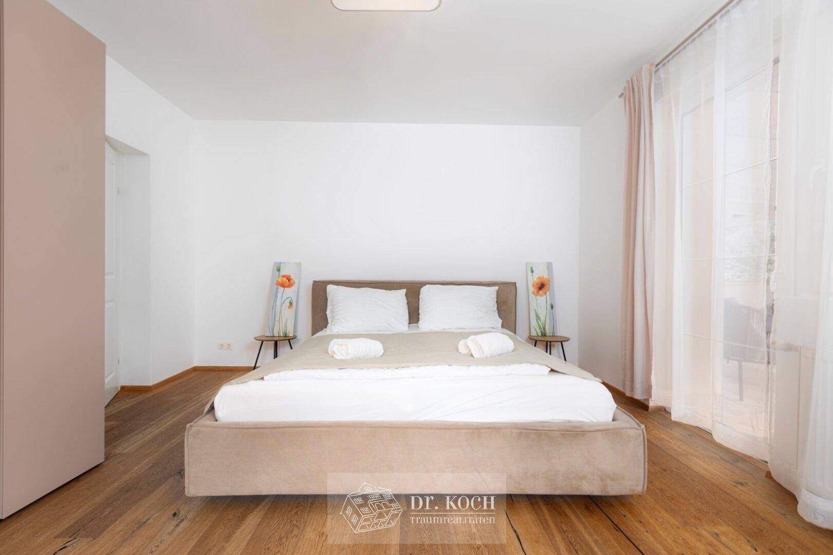 Modernes Schlafzimmer mit Holzboden, beigem Bett und minimalistischer Dekoration für eine ruhige Atmosphäre.