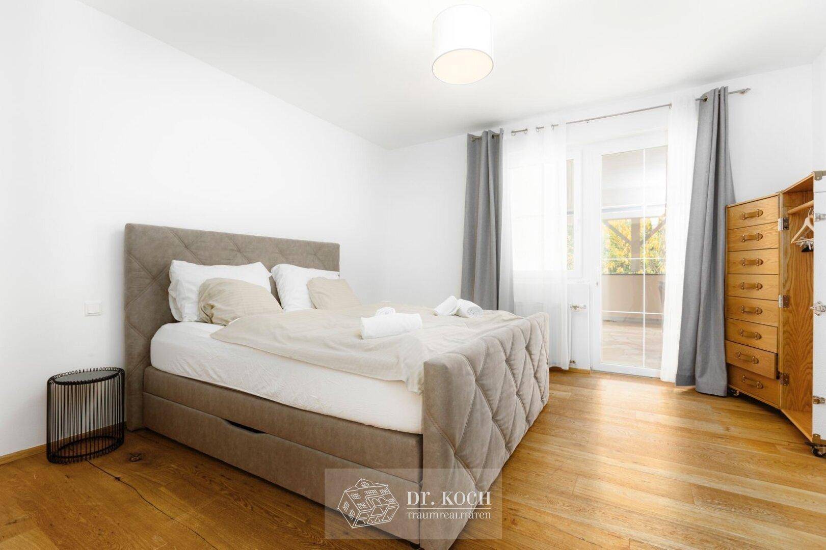 Schlafzimmer mit Holzboden, bequemen Bett und direktem Zugang zu einem sonnigen Balkon.