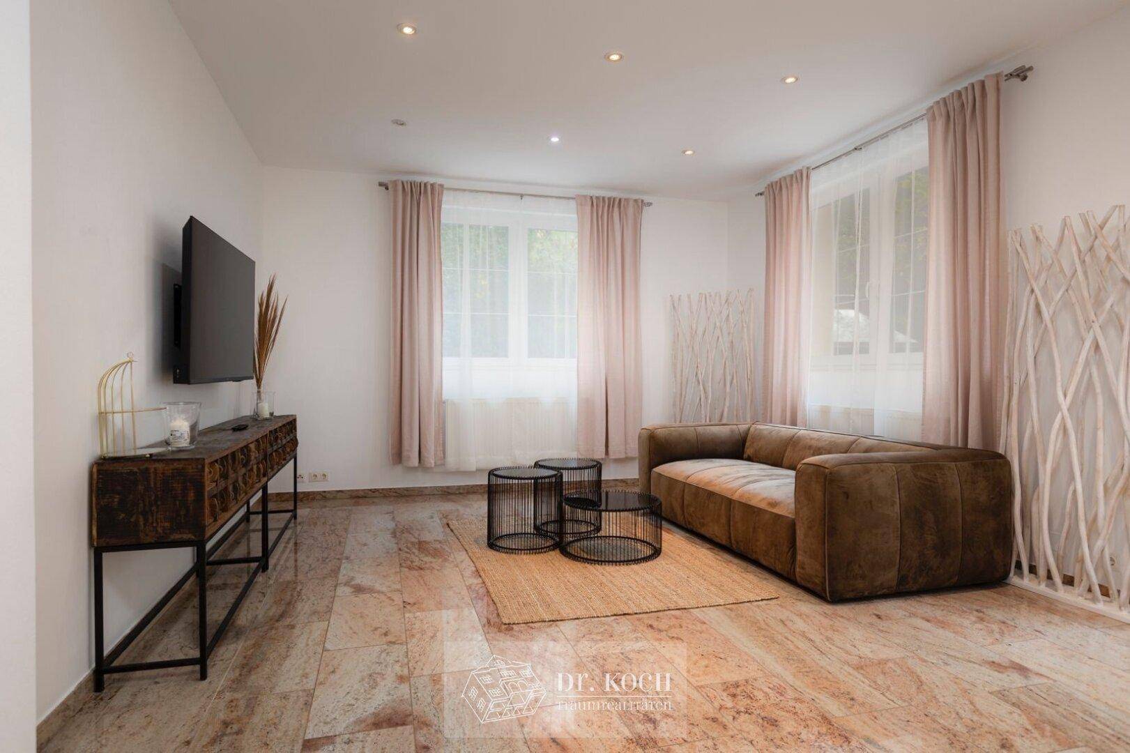 Gemütliches Wohnzimmer mit modernem Sofa, Fernseher und hellem Marmorboden, ideal zum Entspannen.