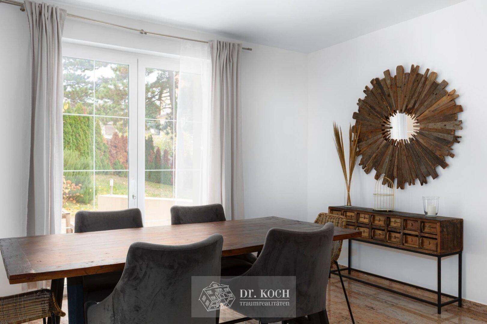 Eleganter Essbereich mit Holztisch, dekorativem Spiegel und Blick in den grünen Garten.