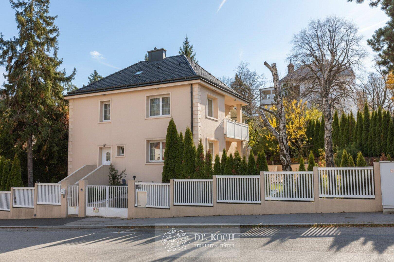Attraktives Einfamilienhaus mit gepflegtem Vorgarten und weißem Zaun an der Straße.
