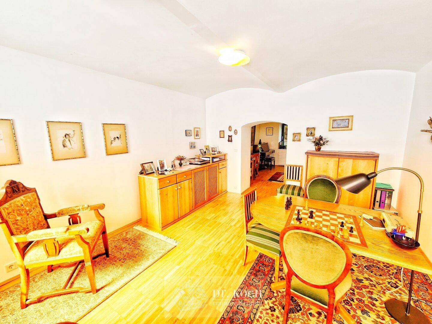 Helles Wohnzimmer mit Holzfußboden, traditionellen Möbeln und einem Schachbrett für gemütliche Abende.