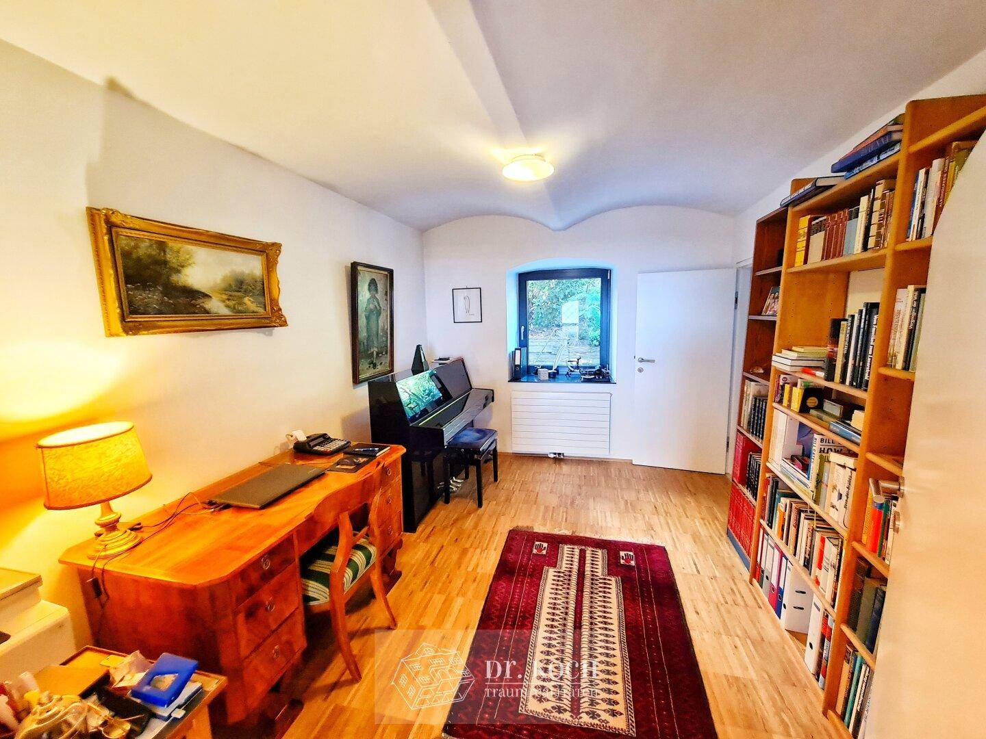 Gemütliches Arbeitszimmer mit Holzschreibtisch, Klavier und einem Bücherregal für eine inspirierende Atmosphäre.