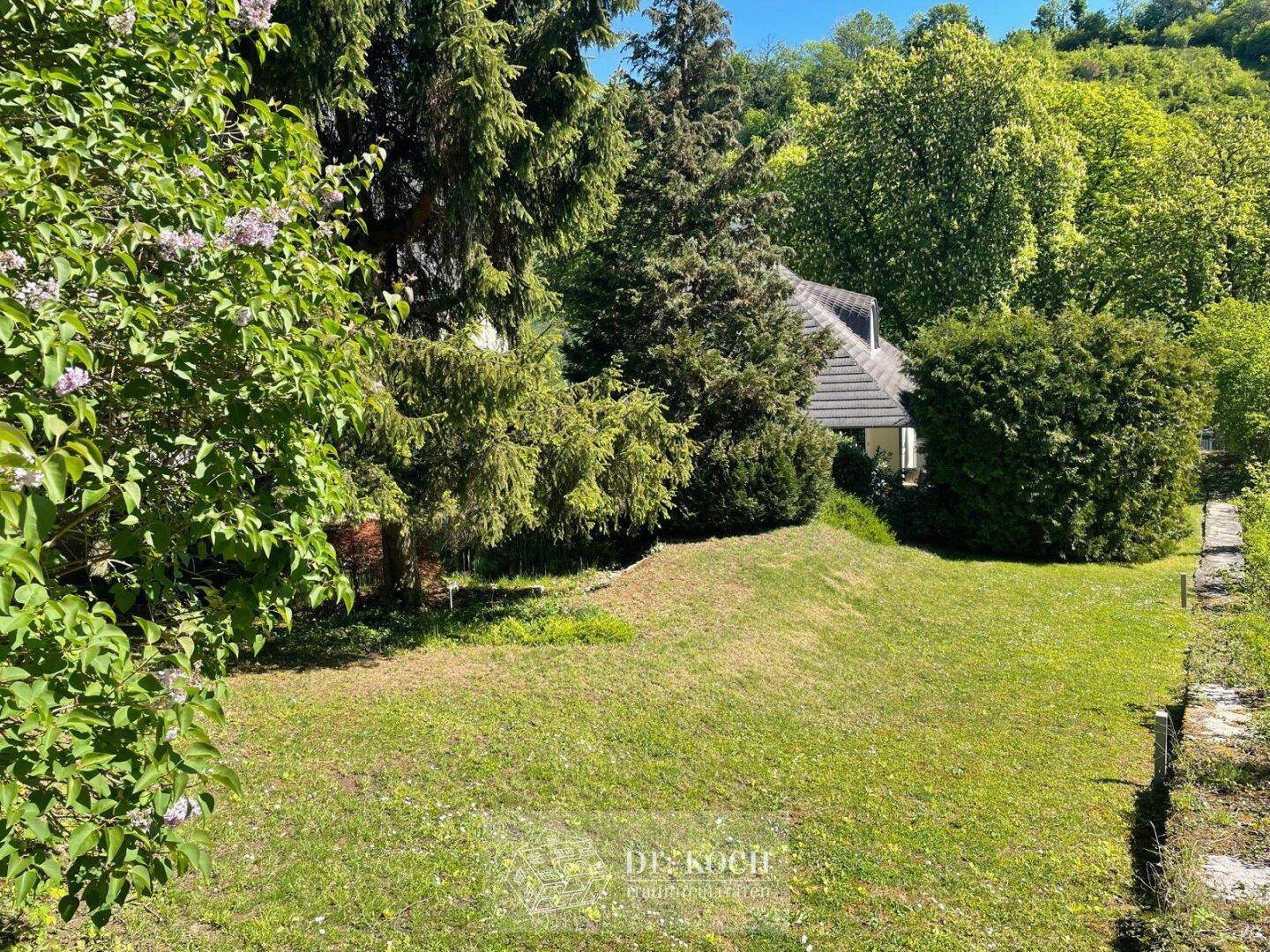 Weitläufiger Garten mit Rasenfläche und Blick auf das charmante Haus im Grünen.