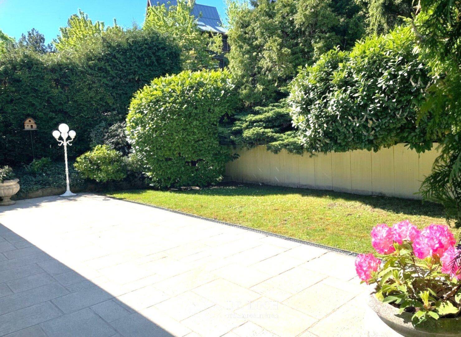 Geräumige Terrasse mit gepflegtem Rasen und blühenden Pflanzen, ideal für Entspannung.