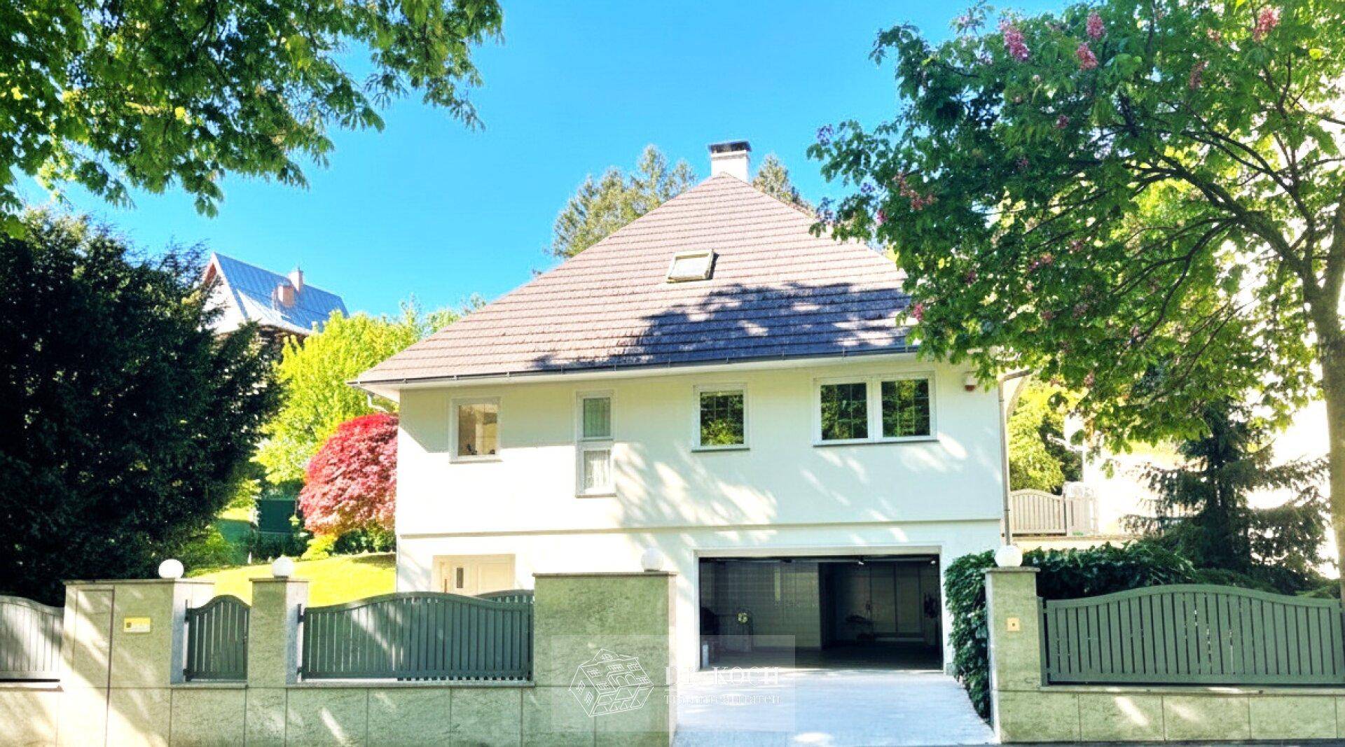 Attraktives Einfamilienhaus mit Garage, gepflegtem Vorgarten und Mansarddach.