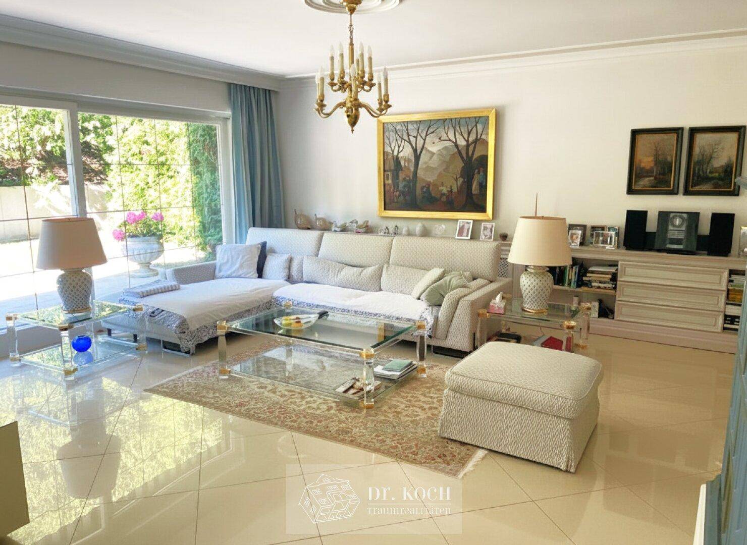 Helles Wohnzimmer mit großen Fenstern, eleganten Möbeln und Zugang zum Garten.