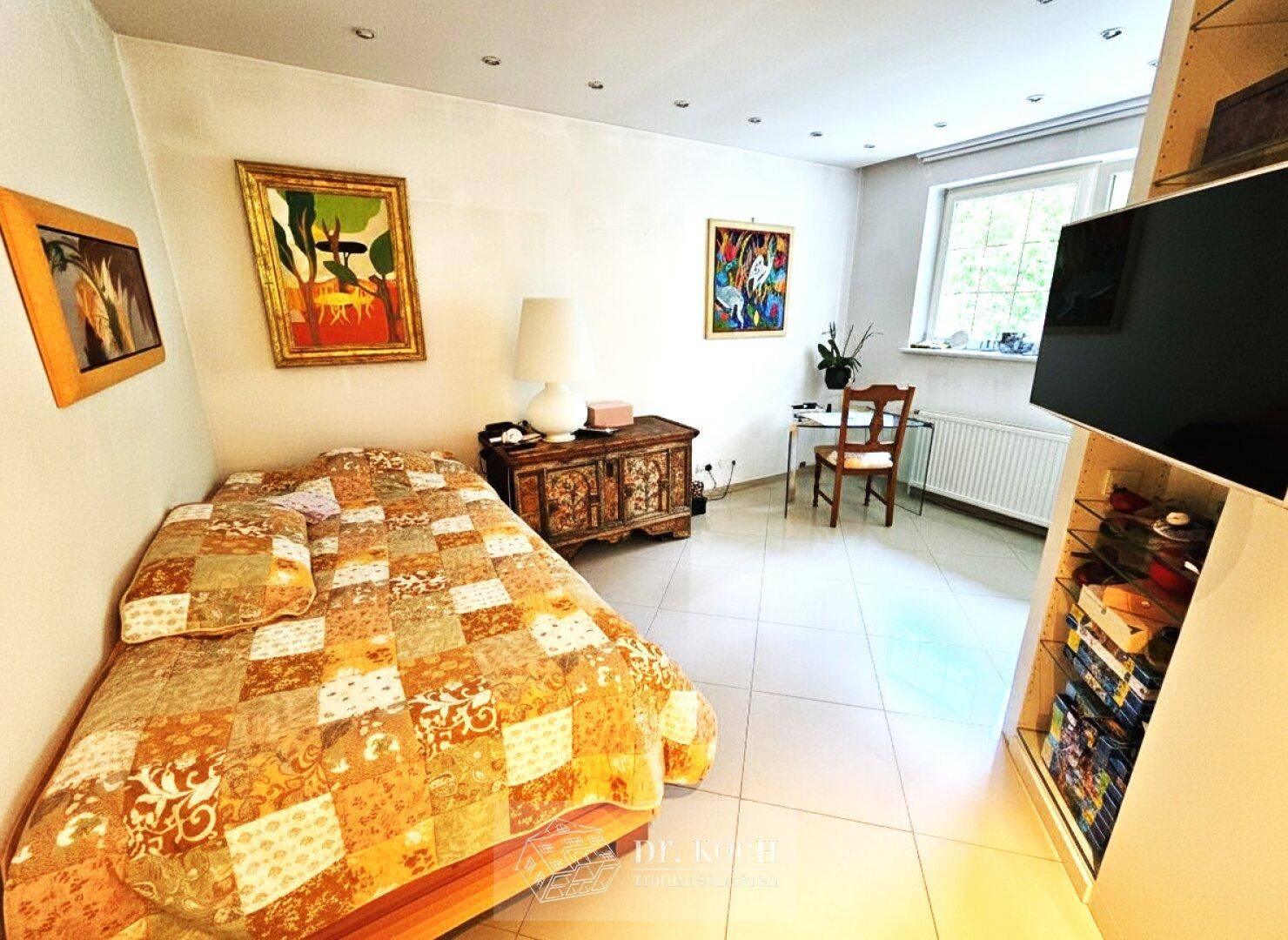 Gemütliches Schlafzimmer mit Fliesenboden, Fenster und moderner Einrichtung.