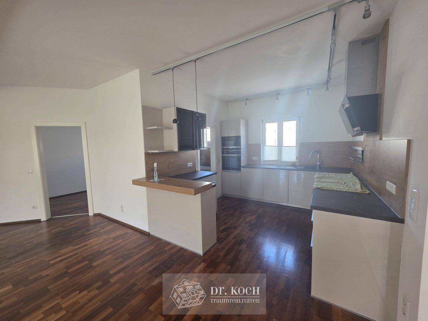 Moderne offene Küche mit Holzboden und integriertem Essbereich, verbunden mit dem Wohnzimmer.