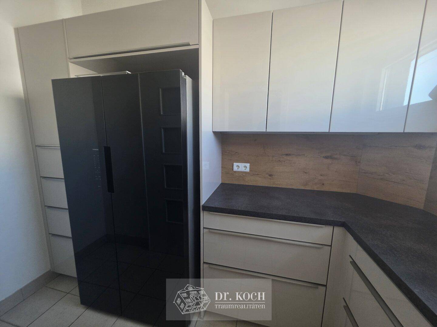 Detailansicht der modernen Küche mit großem schwarzem Kühlschrank und hellen Schränken.
