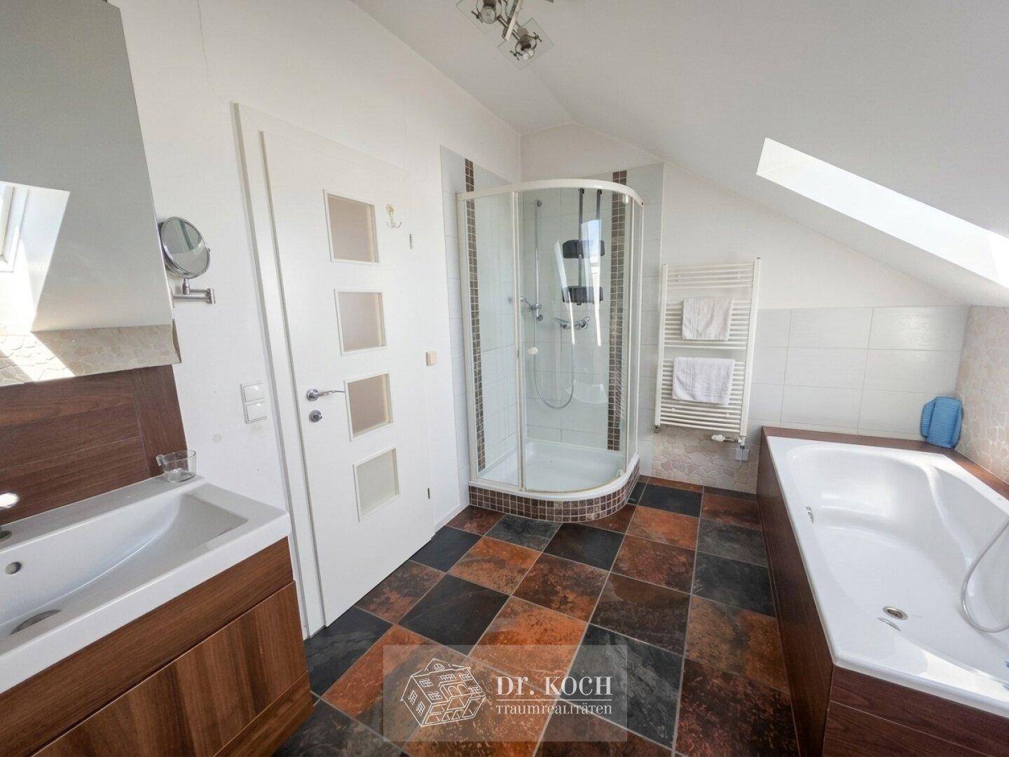 Modernes Badezimmer mit Badewanne, Dusche, Doppelwaschbecken und farbigen Fliesen.