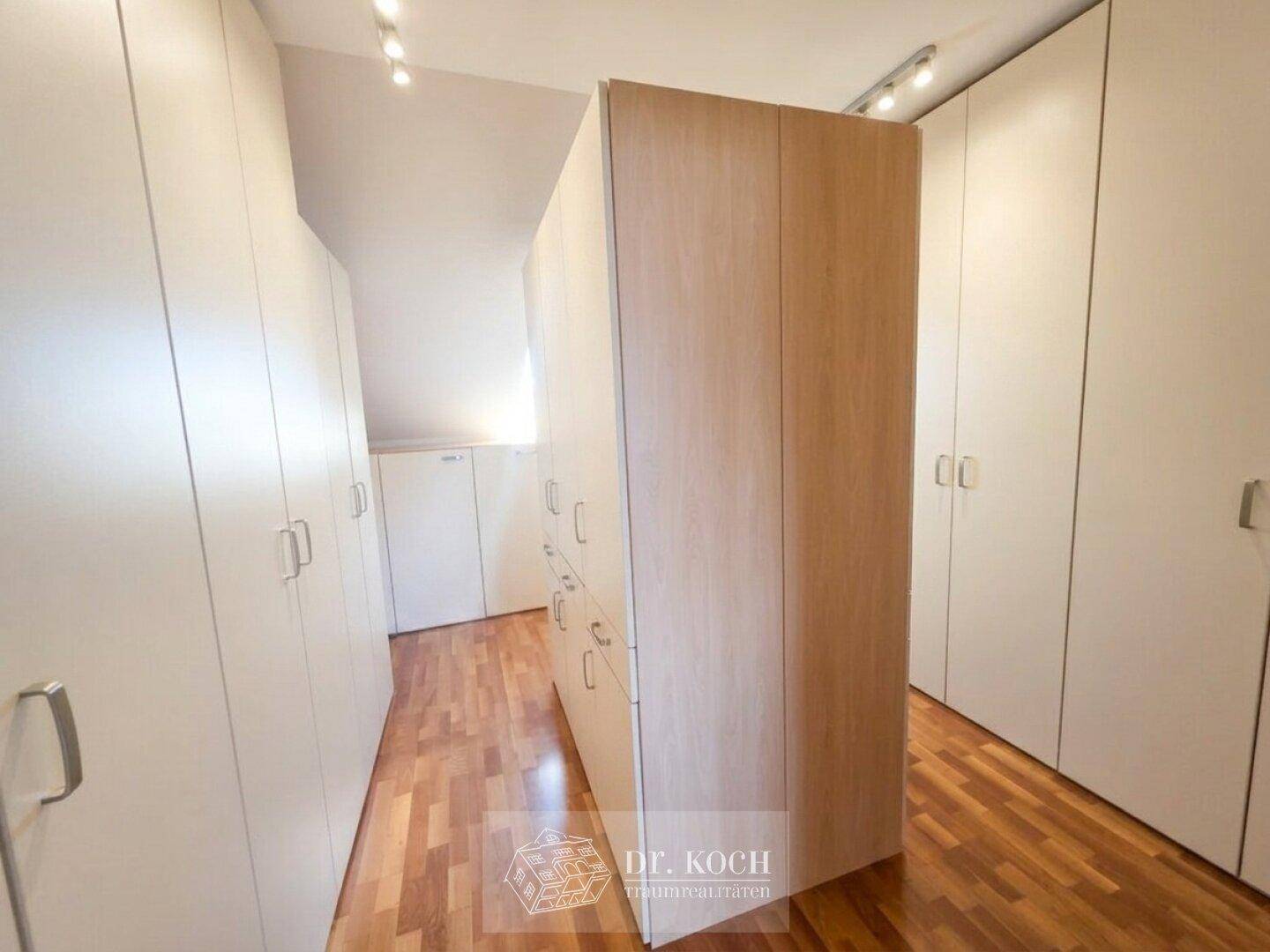 Geräumiger Ankleidebereich mit vielen Einbauschränken und Holzboden für optimale Organisation.