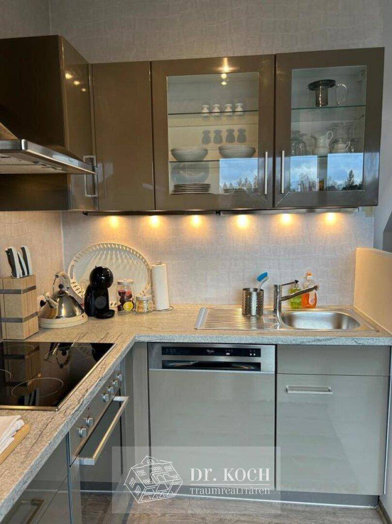 Moderne Küche mit glänzenden grauen Schränken, Granitarbeitsplatte und integrierten Geräten.