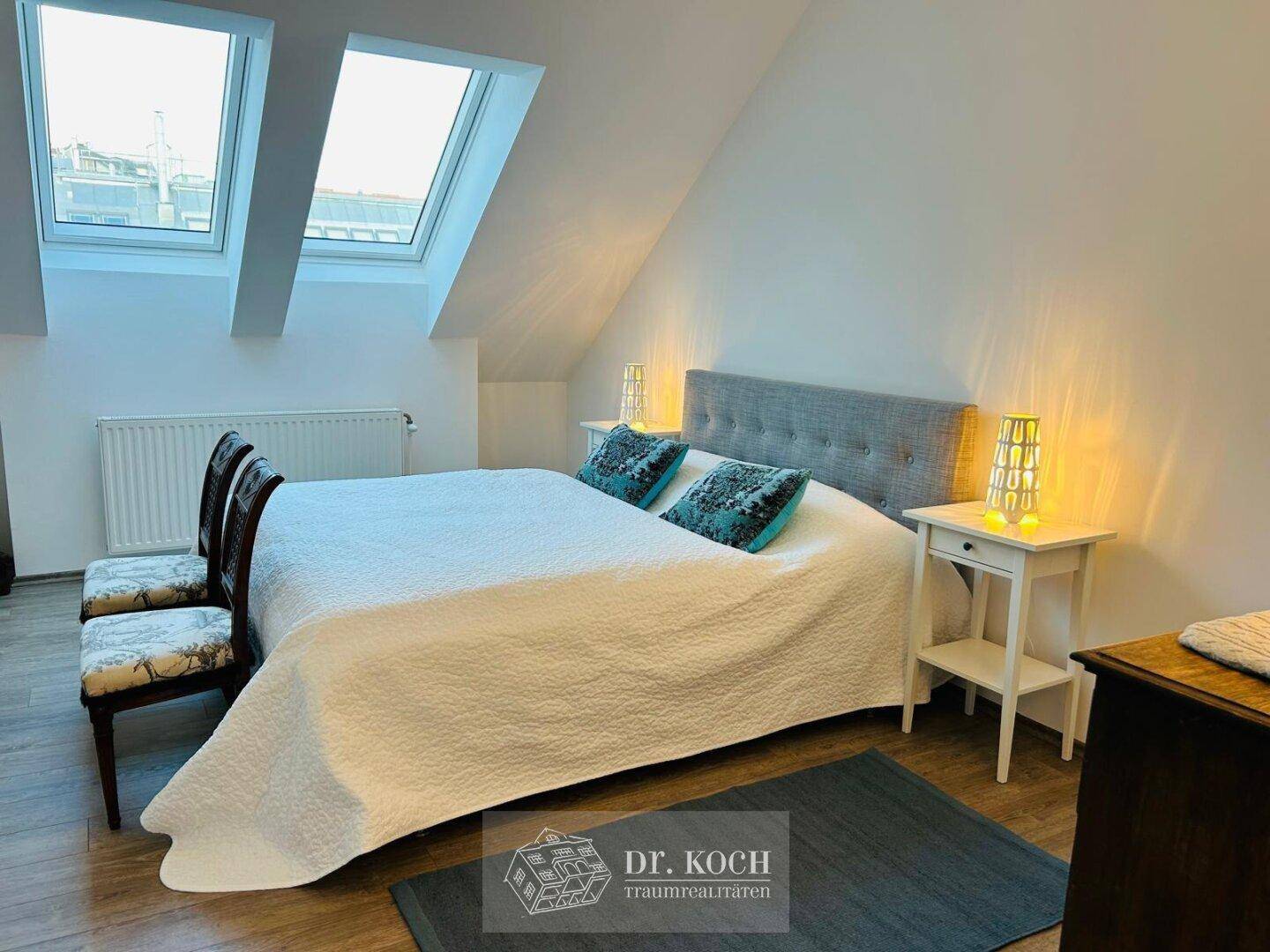 Helles Schlafzimmer im Dachgeschoss mit Doppelbett, Nachttischen und zwei Dachfenstern.